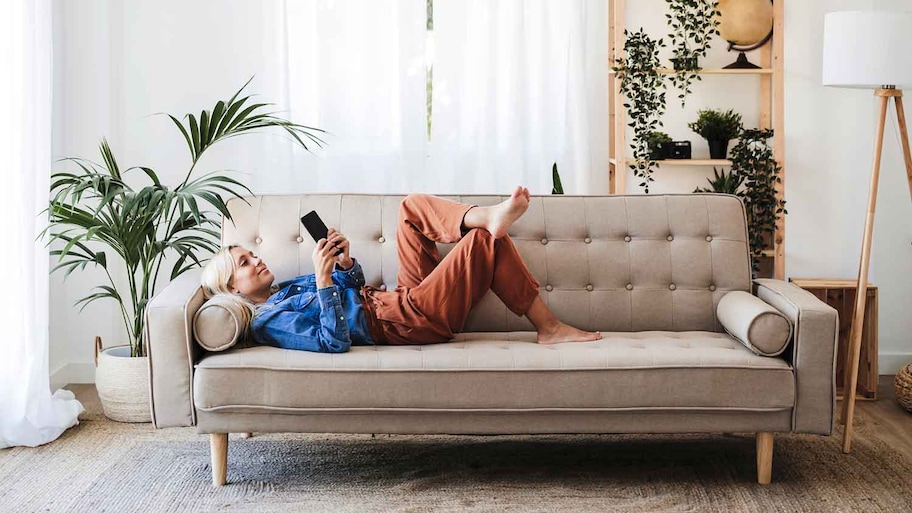 Woman lying on the sofa checking her phone