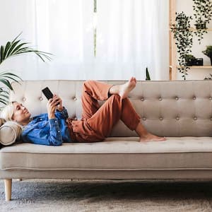 Woman lying on the sofa checking her phone