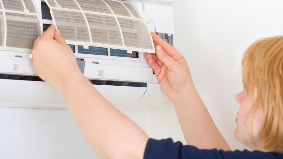 A woman removing air filters from AC unit