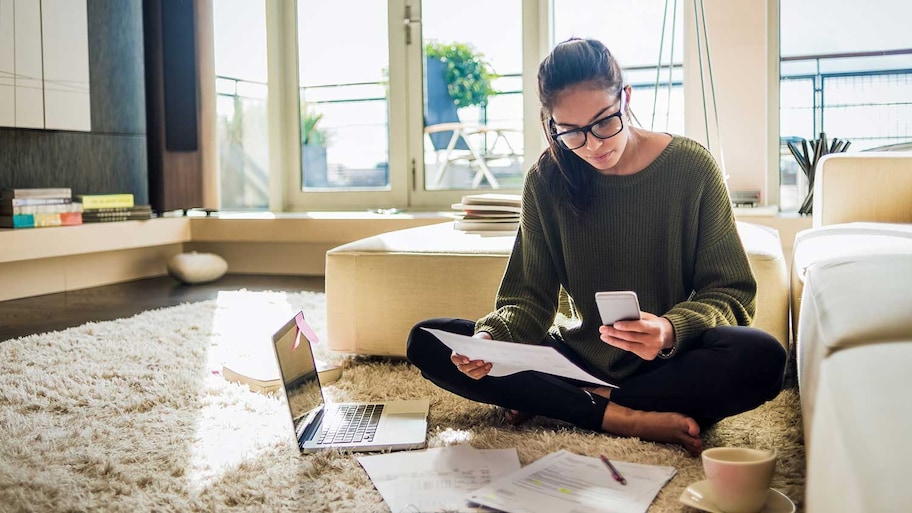 Woman sitting on the floor using laptop and phone