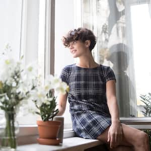 woman looking at phone near open window