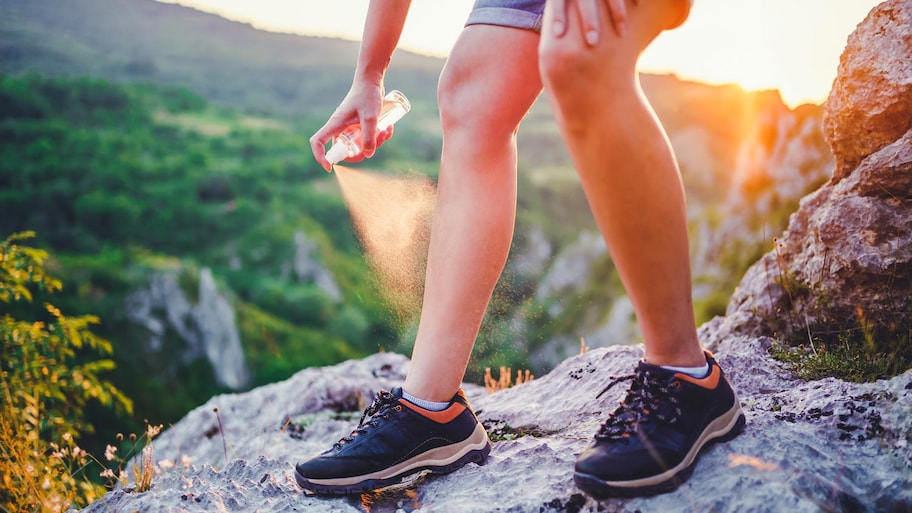 Detail of a woman spraying her leg with diy mosquito repellent