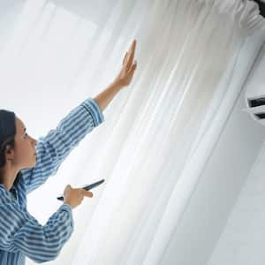 A woman turning on AC unit