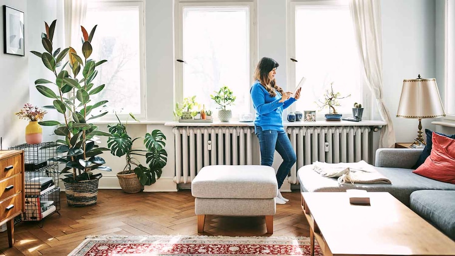 A woman using a tablet standing in front of a radiator