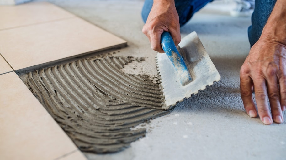 A worker applying mortar to the subfloor