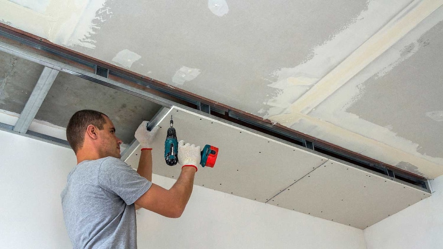 A worker installing a drop ceiling