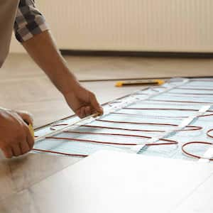 Worker installing electric underfloor heating