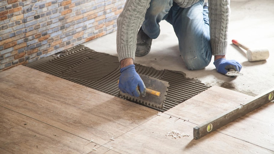  A worker laying new ceramic tiles over subfloor