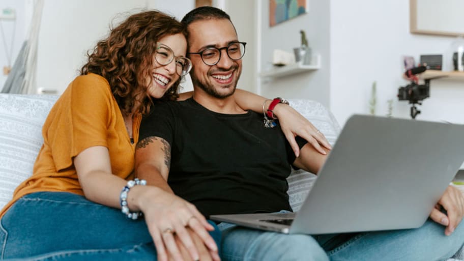 young couple sitting on couch with laptop