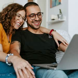 young couple sitting on couch with laptop