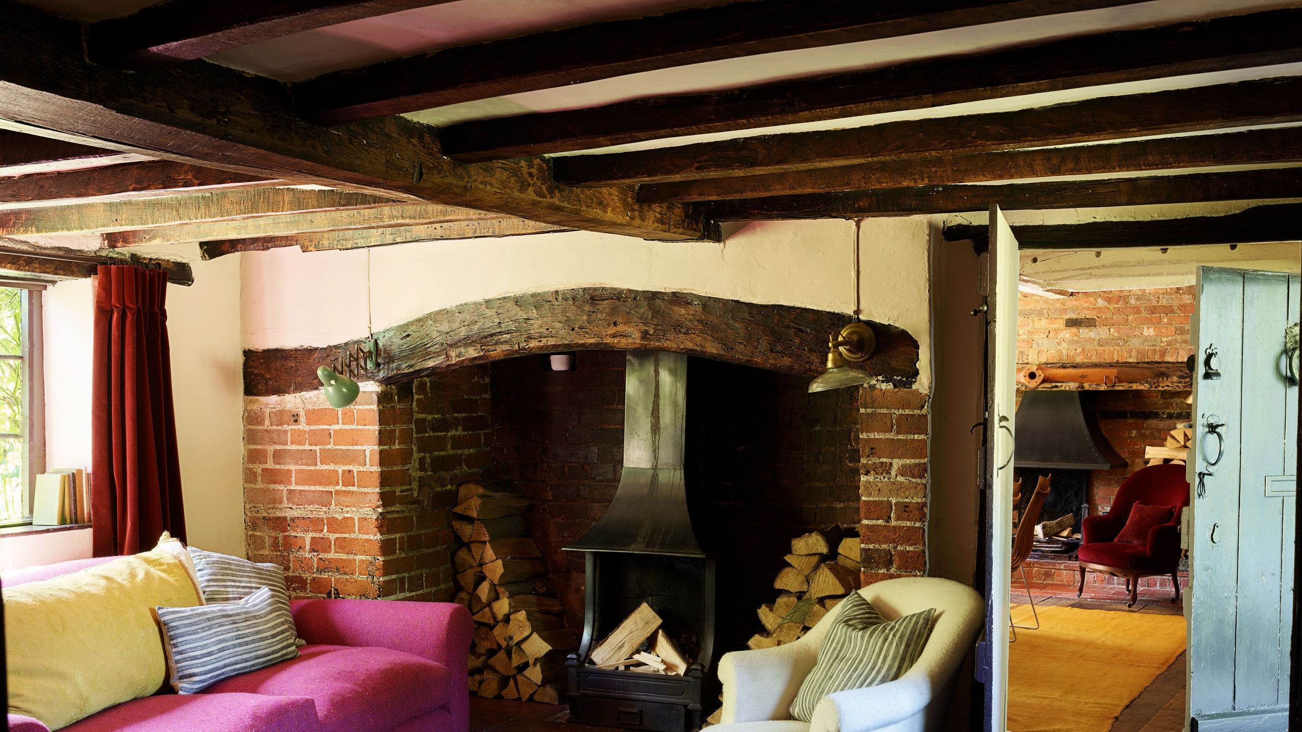 Living room with a fuchsia couch and exposed beams.