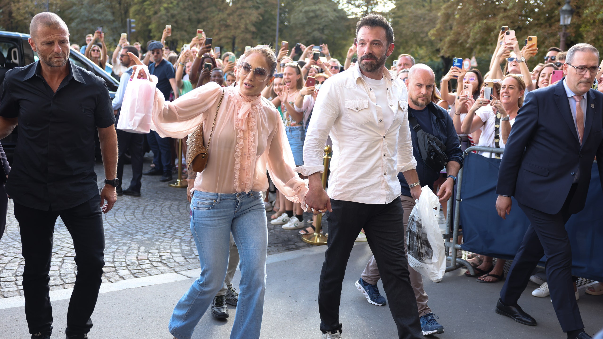 Jennifer Lopez Ben Affleck walking handinhand flanked by security and waving to crowd of onlookers