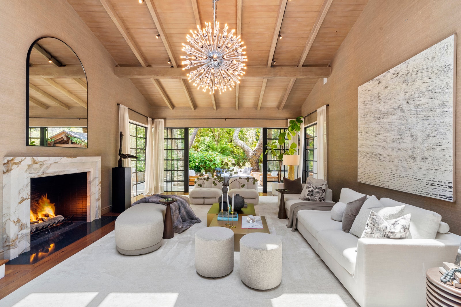 Open living area of Jennifer Lopezs former home with vaulted ceilings marble fireplace white sofa and seating french...