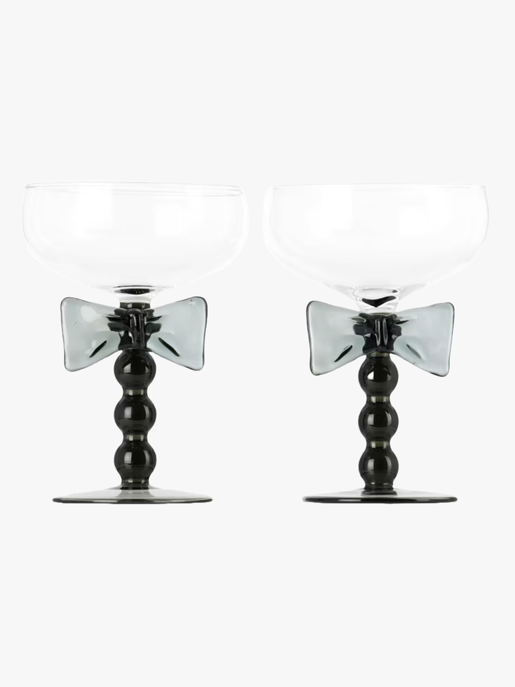 Pair of coupe glasses with a black glass bow tie design on the handle