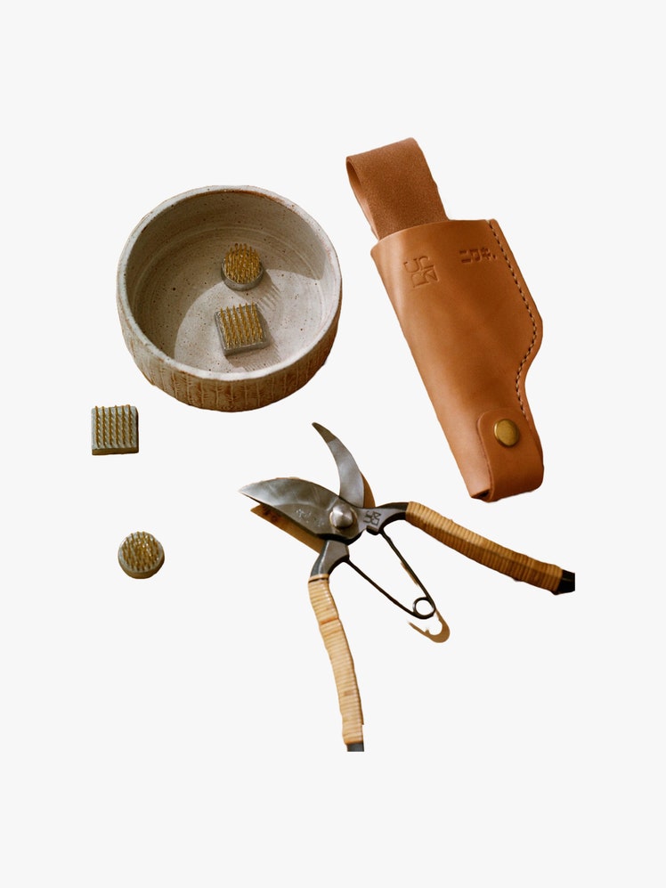 Pruning shears leather holster shallow ceramic bowl and set of brass pins to hold floral arrangements.