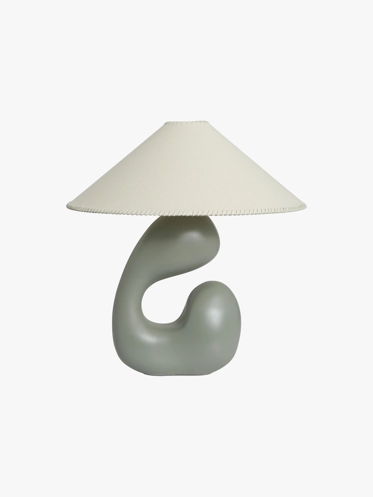 Table lamp with a muted green sculptural base and a beige lampshade with accent stitching along the edge.