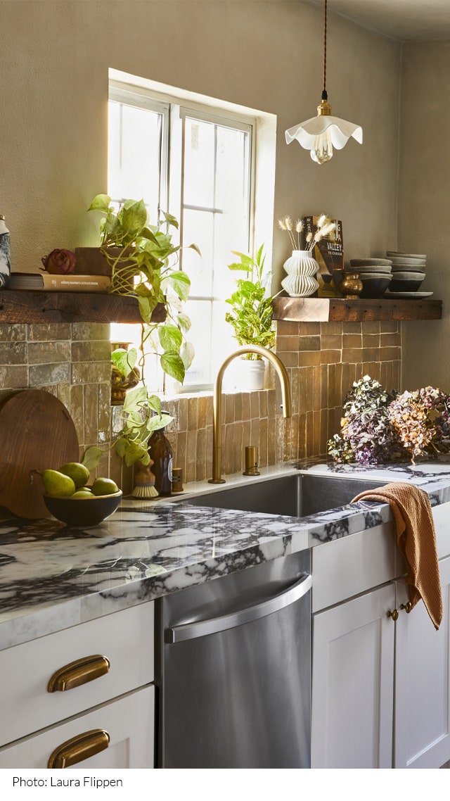 Kitchen designed by Sagrada Studio including a kitchen sink below a window with a marble countertop green tiled...