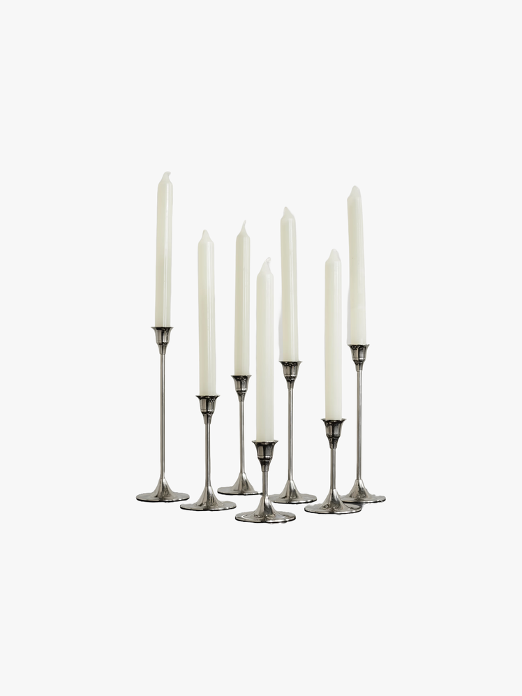 Set of seven nickel candlesticks with white pillar candles inside them.