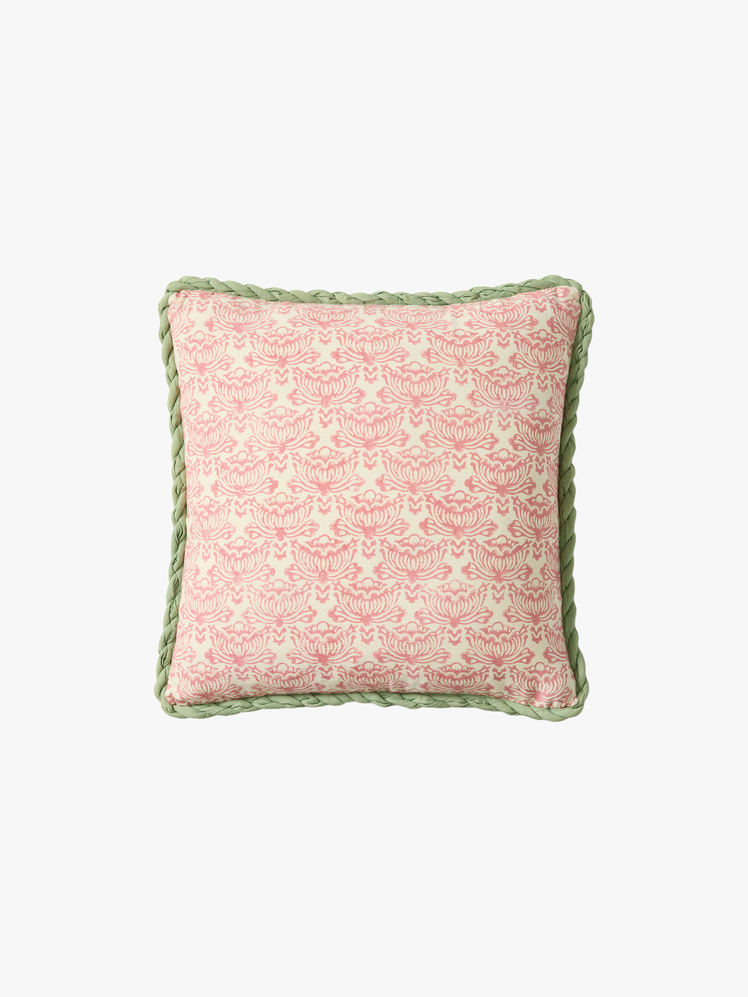 Square pillow with a pink vintageinspired lotus print against a green rope trim.