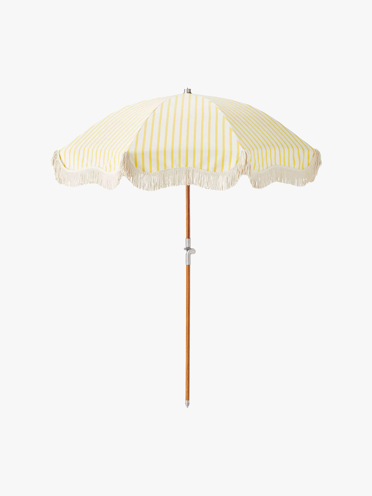 Beach umbrella with a yellow and white striped shade with fringe on the edge.