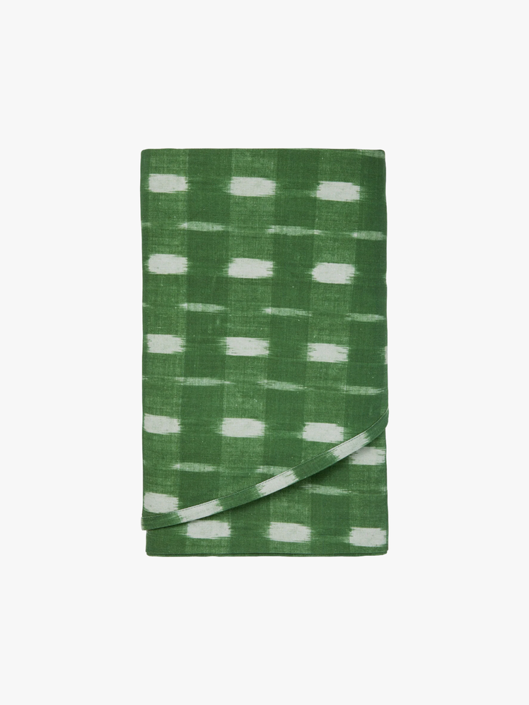 Tablecloth in a green ikat pattern folded up into a rectangle.