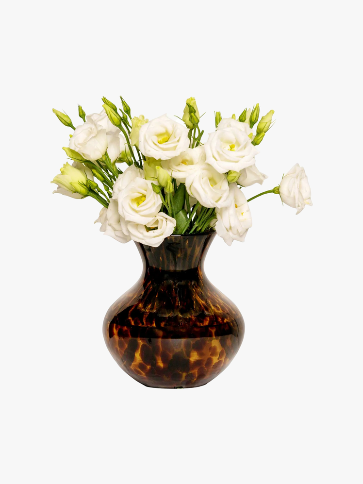 Tortoiseshell vase with a bouquet of white roses in it.