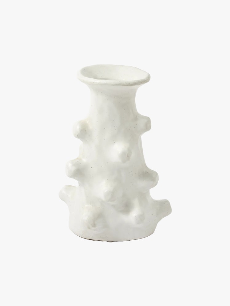 Vase with an organic handsculpted form made to look like a stem with thorns on it in an offwhite color.