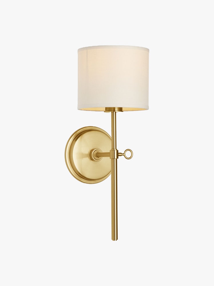 Brass wall sconce with a linen shade and a decorative turnkey socket.