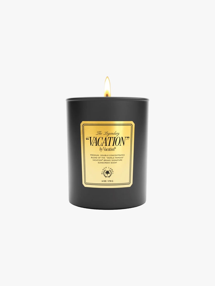 Lit Vacation candle in a black container with a gold label.