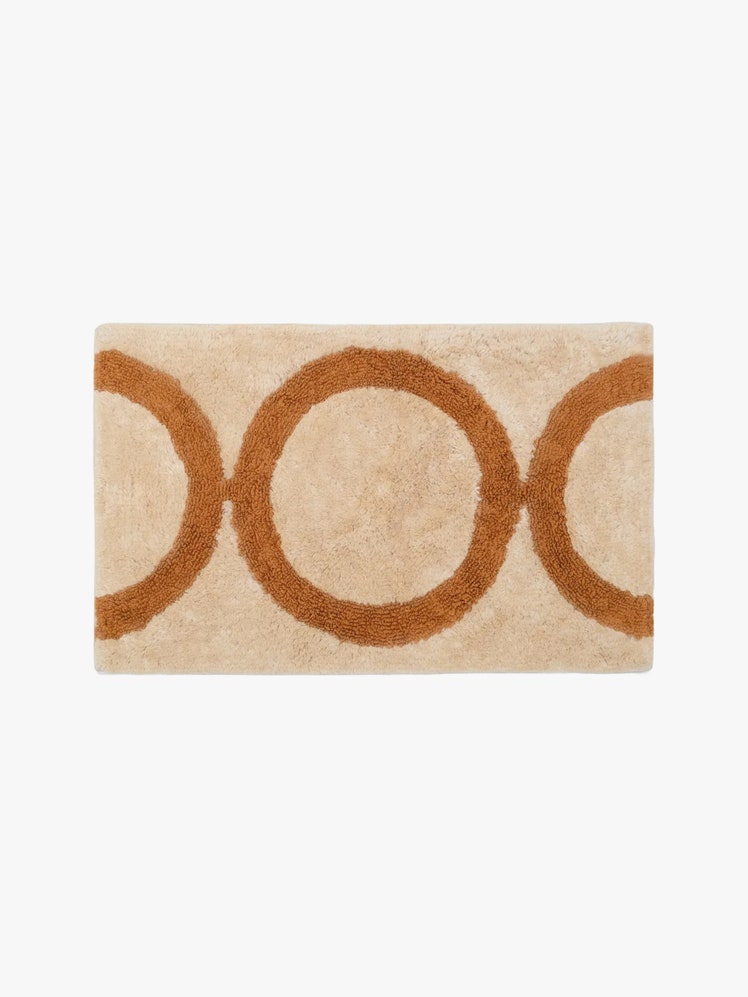 Beige and orange bath mat with a circular pattern.