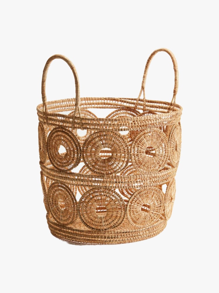 Round storage basket in straw with a circular woven design and two handles.