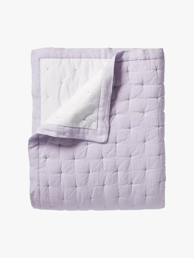 Lilac quilt folded into a rectangle with one corner peel up to show the interior facing.