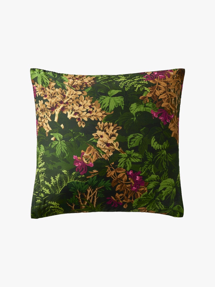 Pillow with a dark green botanical print inspired by a vintage 1901 wallpaper featuring ferns blossoms and ivies .