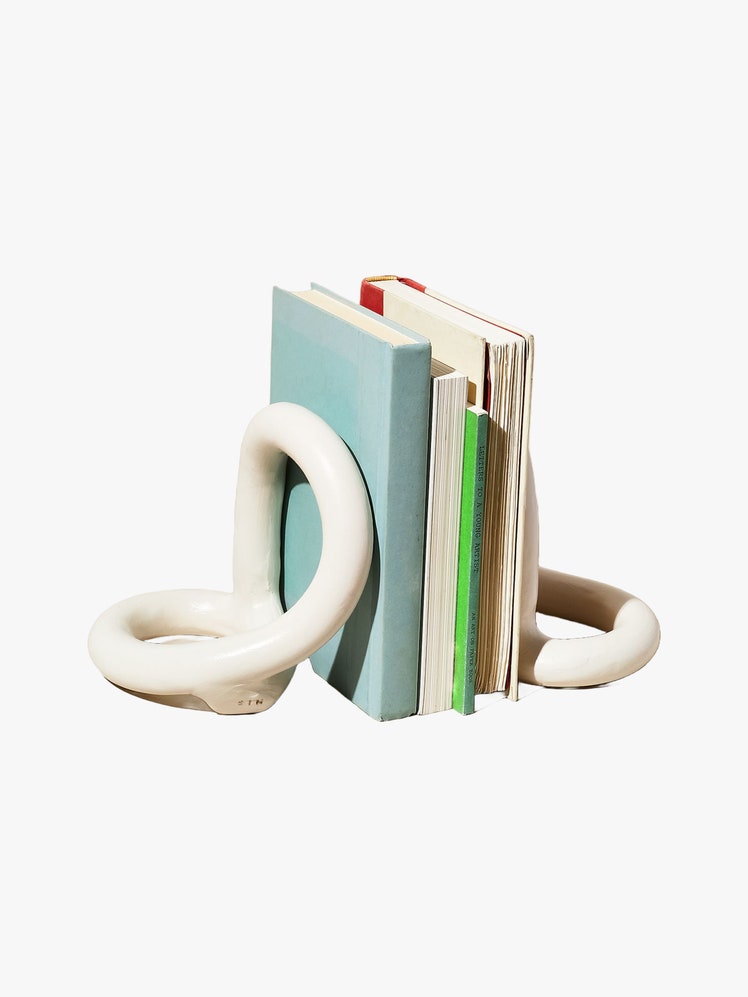 Set of white ceramic coil bookends in looped shapes holding a stack of books between them.