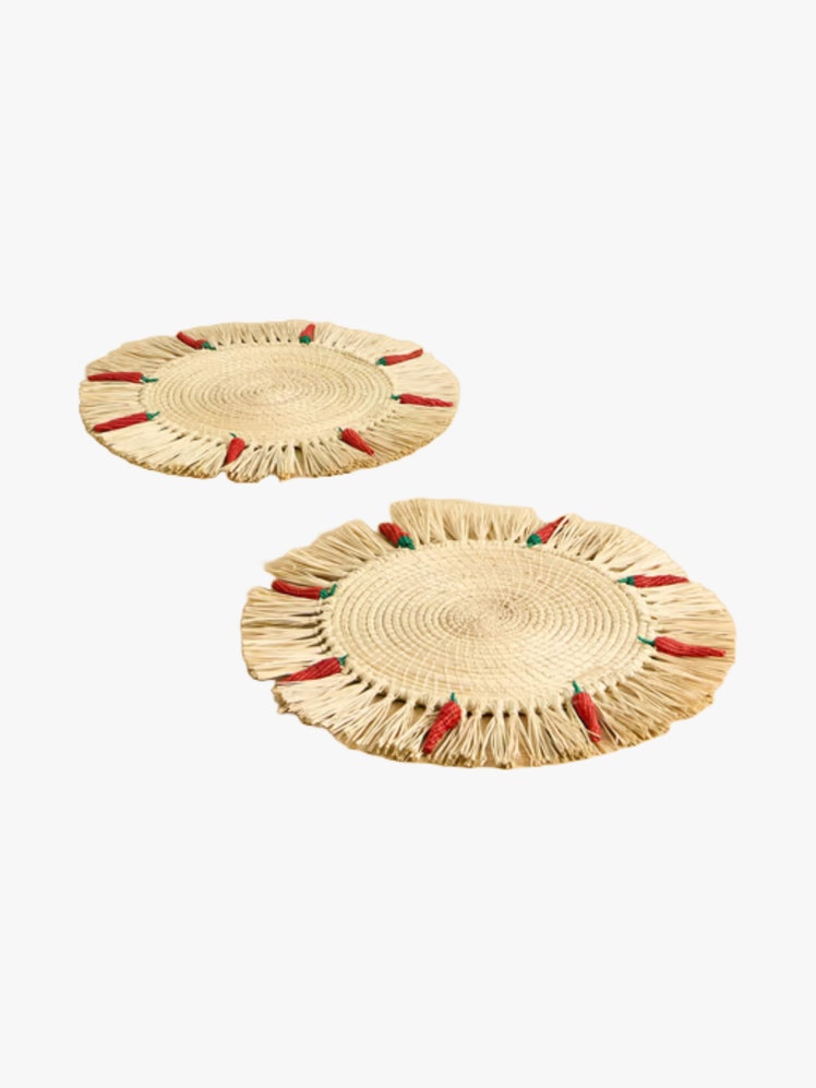 Set of two raffia placemats with fringed edged dotted with chilies.