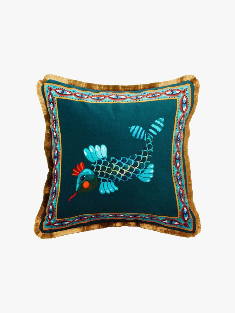 Square pillow with teal blue fabric featuring a fish print and a gold fringed edge.