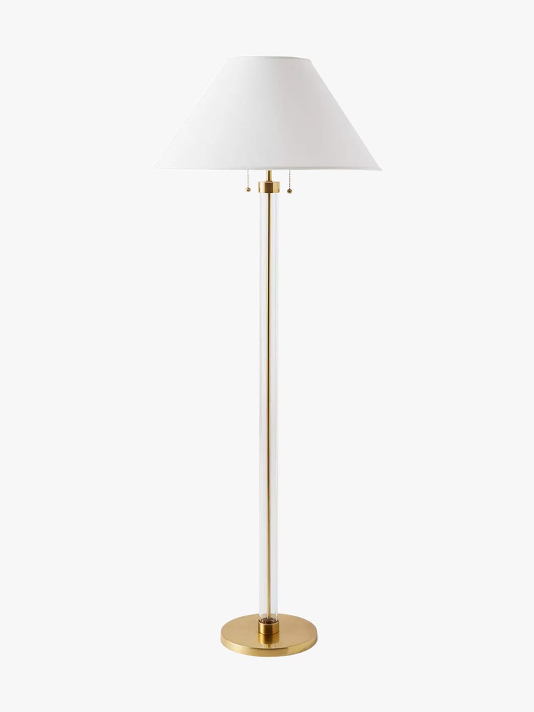 Floor lamp with a clear glass cylindrical base showcasing brass hardware inside. Finished with a tapered shade.