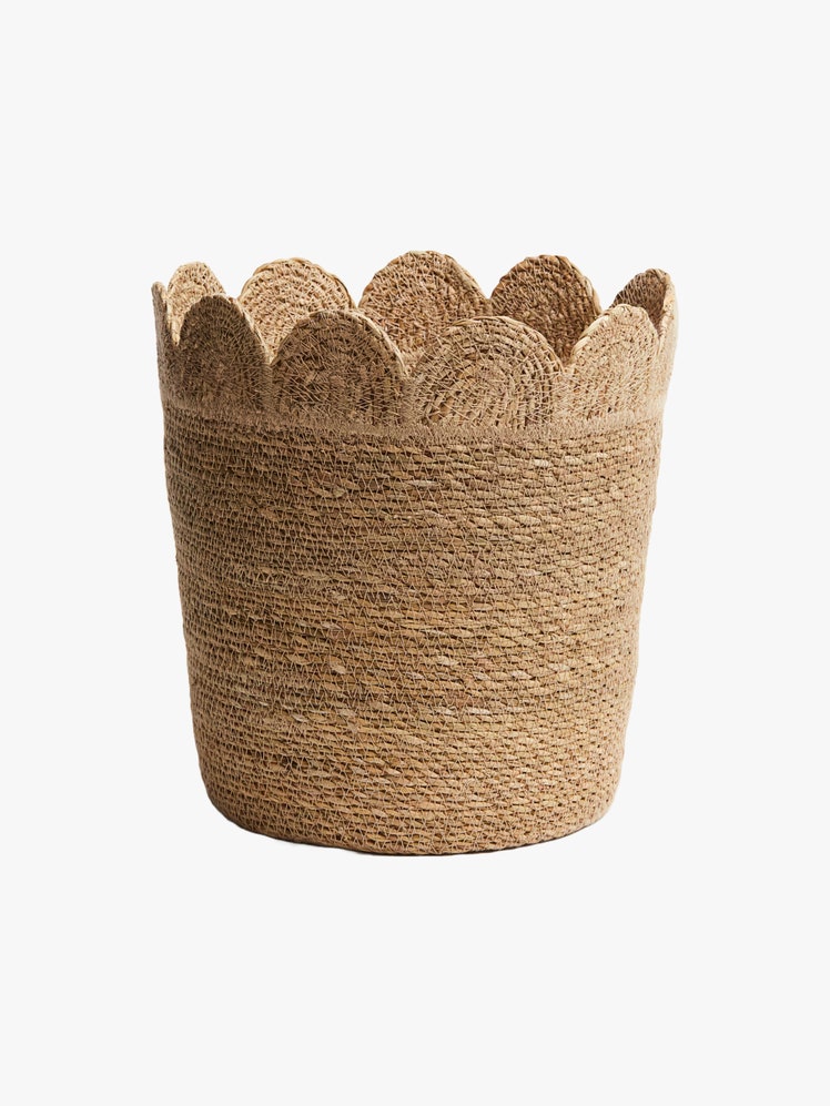 Storage basket in braided seagrass with a scalloped top edge.