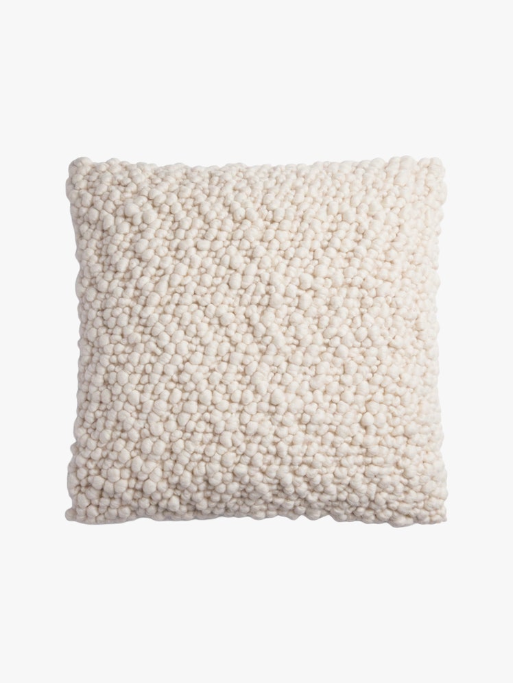 Square pillow with a white pebbled texture wool cover.