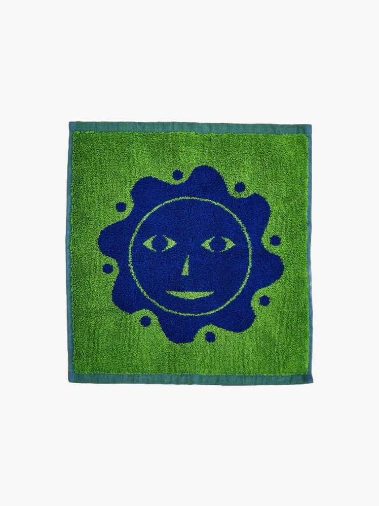 Green washcloth with a dark blue sun face printed on it.