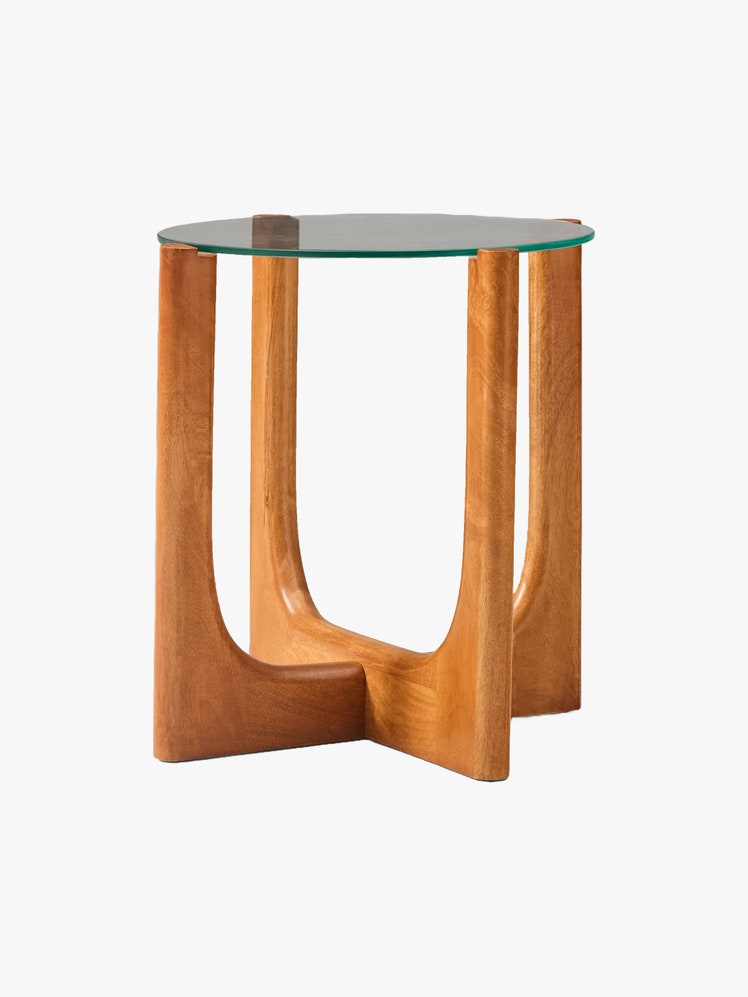 Side table with a circular glass top and ushaped wooden legs.