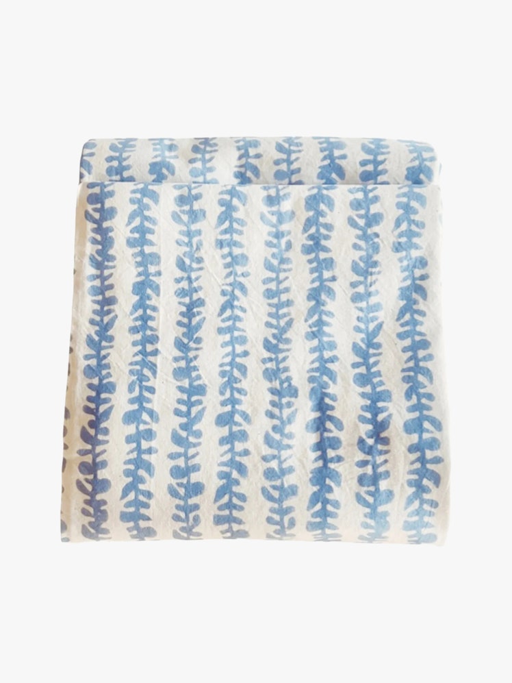 White tablecloth with a blue blockprinted leaf design.