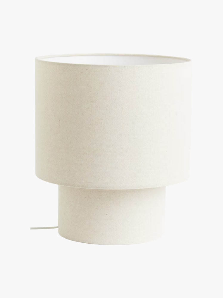 Cylindrical table lamp with linenlook beige fabric on a wire frame.