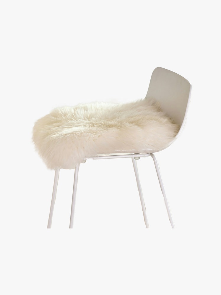 Article Lanna Ivory Sheepskin Seat Pad on a white chair.