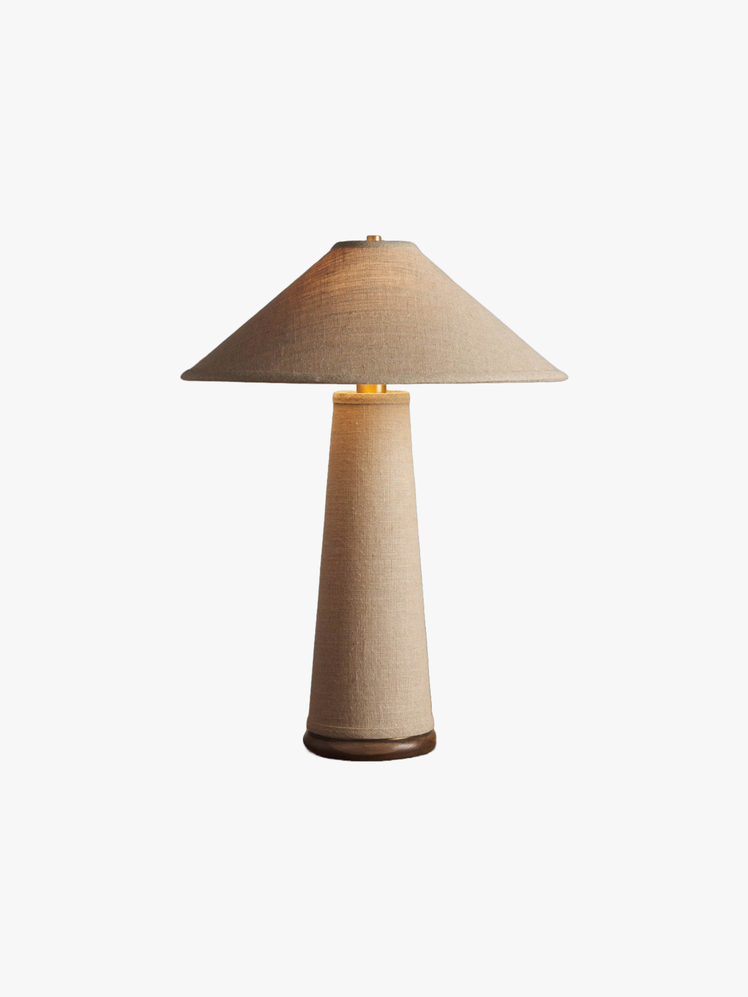 Table Lamp crafted from linen complimented by a sculptural wooden base and brass accents.