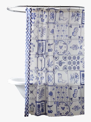 Blue and white shower curtain featuring whimsical icons allover in a tiled design hanging over a bathtub.