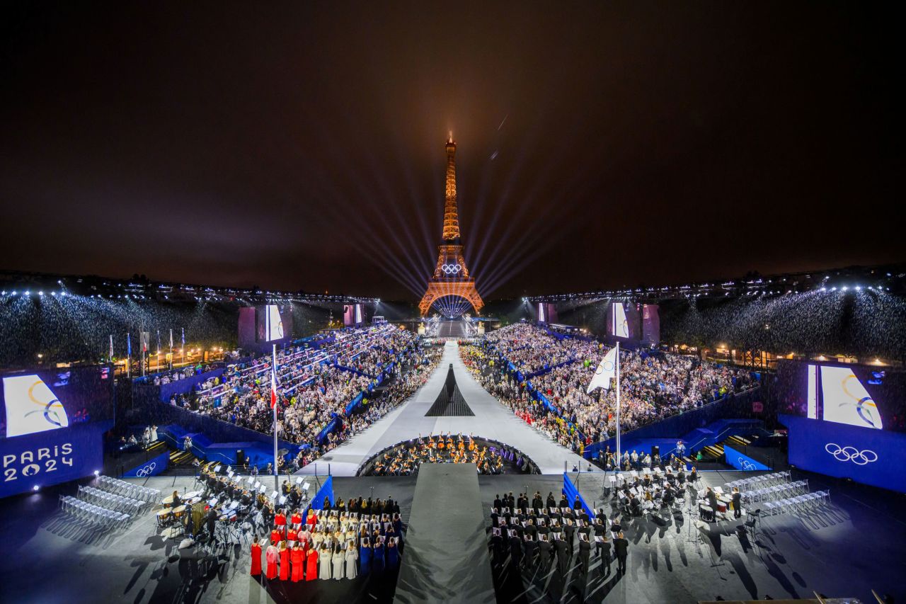 The Eiffel Tower shines in the background while the Olympic flag is raised during the opening ceremony in Paris on July 26. 