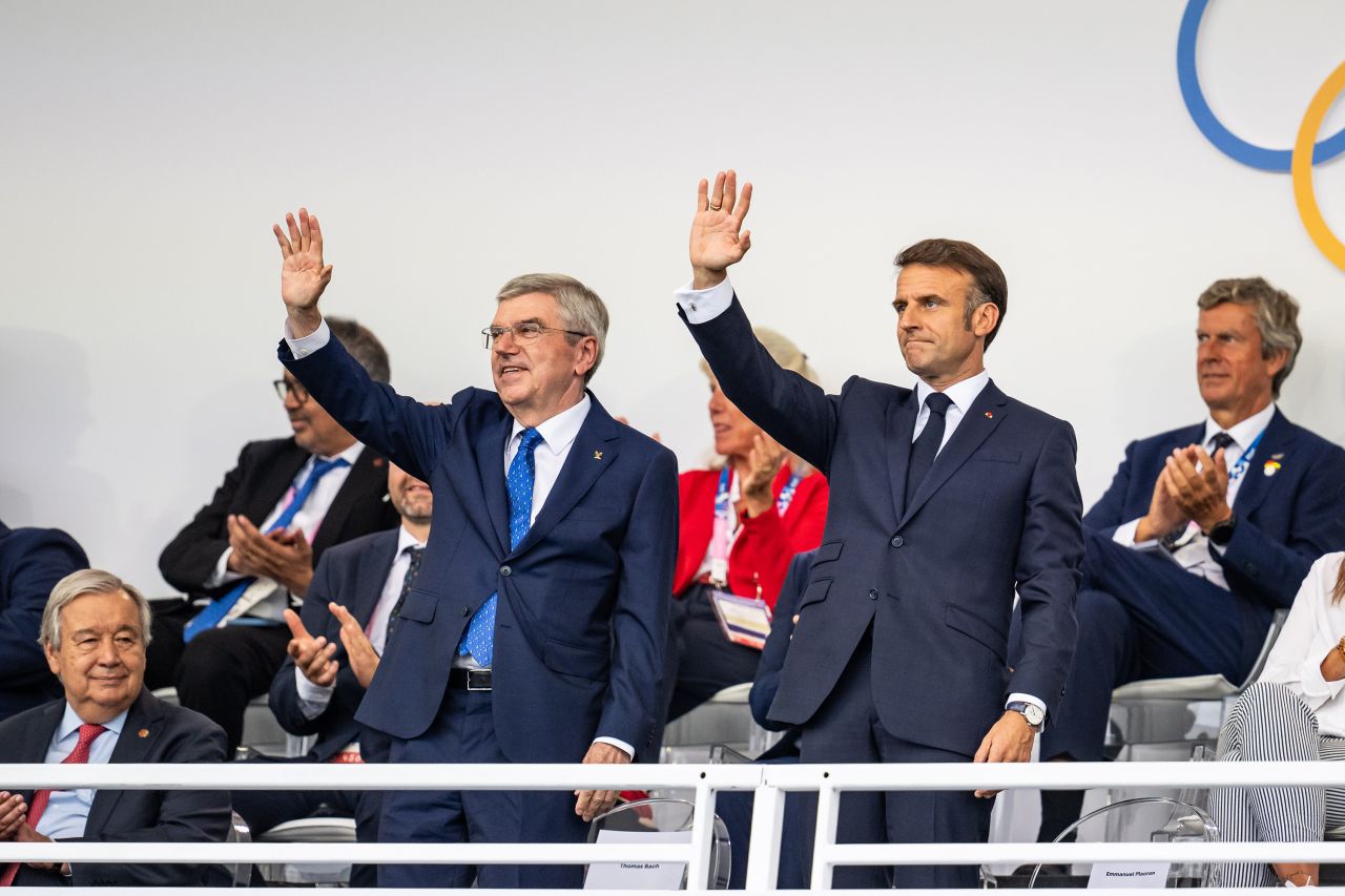 French President Emmanuel Macron (R) and President of International Olympic Committee Thomas Bach wave during the opening ceremony of the Olympic Games Paris 2024 on July 26.