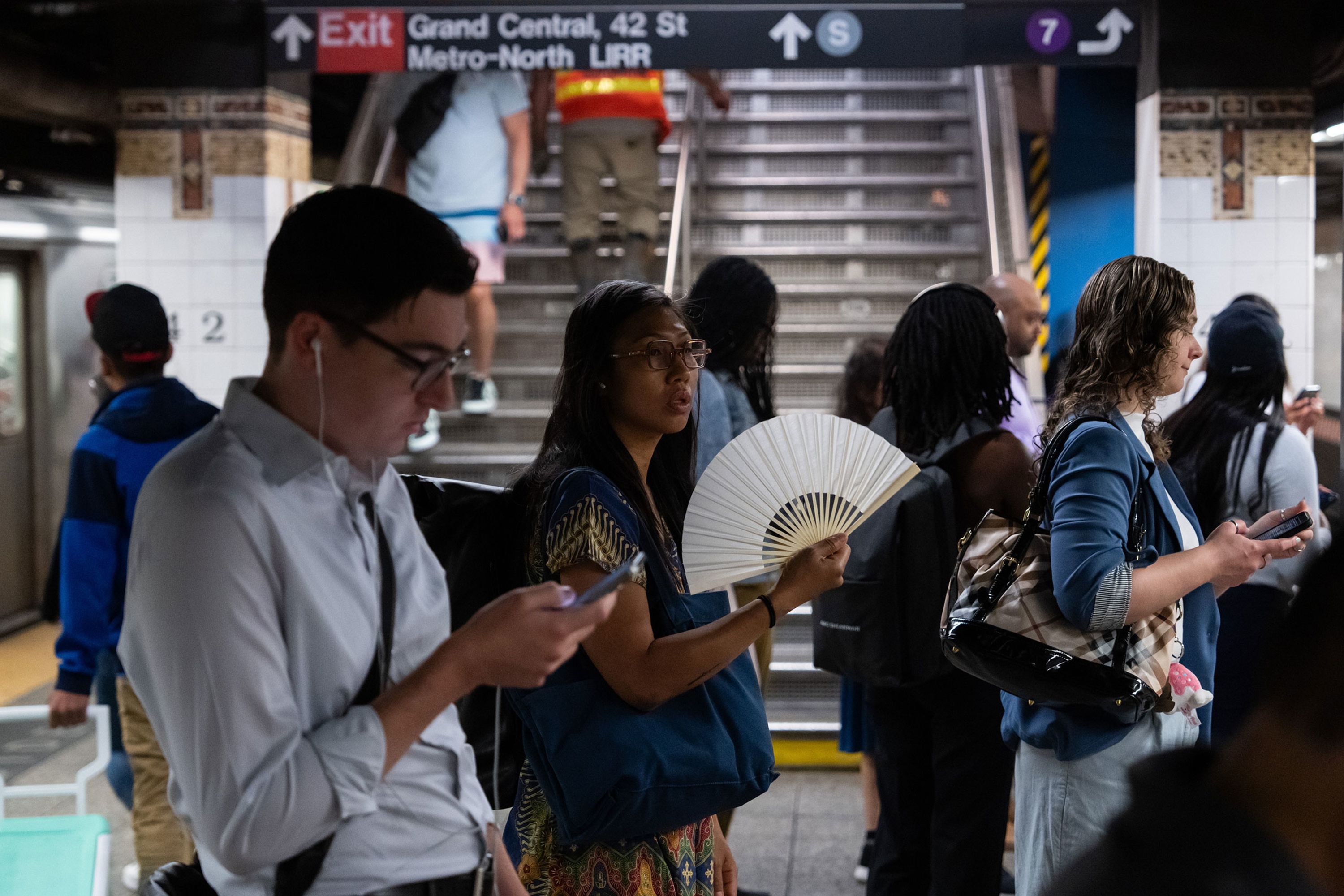 A commuter uses a fan to cool off while waiting for a train at a New York City subway station on Thursday, June 20.