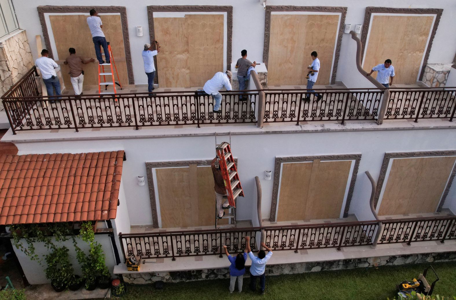 Workers install wood panels to cover glass doors at a hotel in Playa del Carmen, Mexico, on Wednesday.